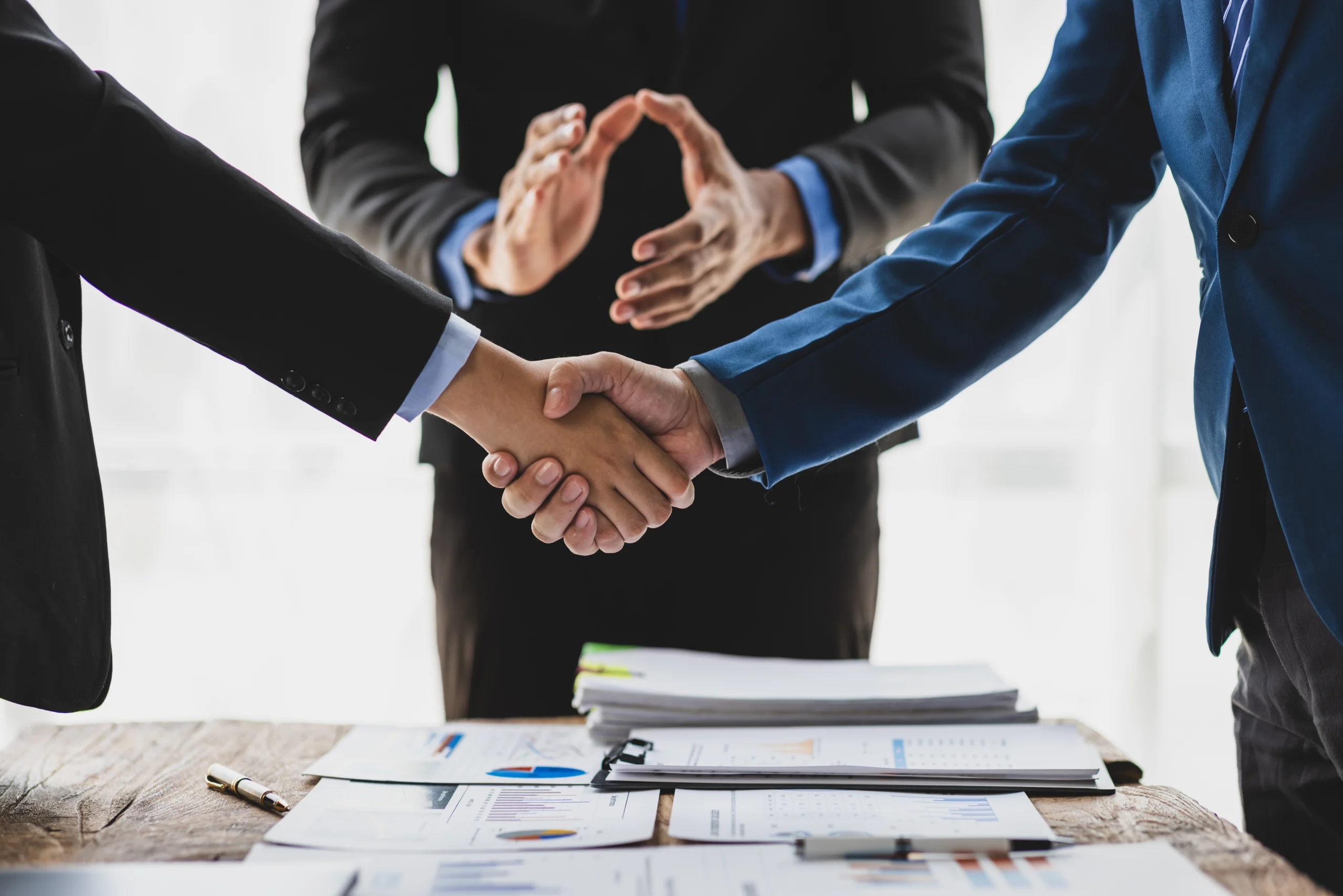 Vertragspartner geben sich die Hand und Mediator steht dahinter